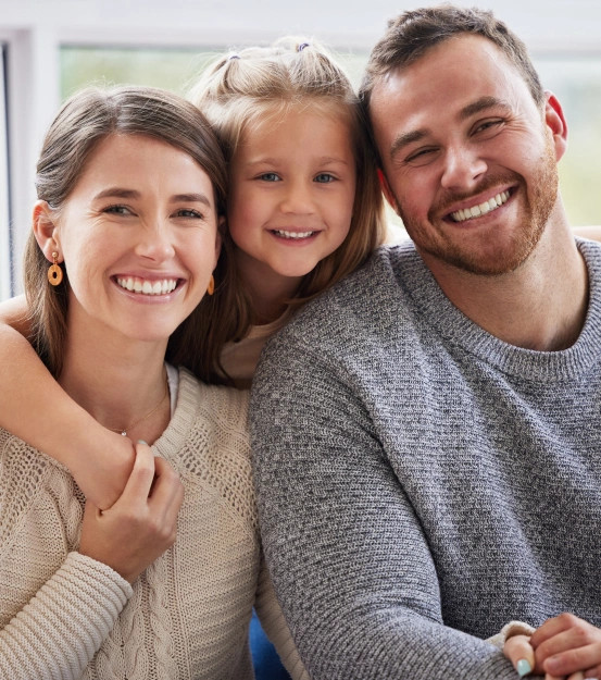 Family of three smiling together for a portrait